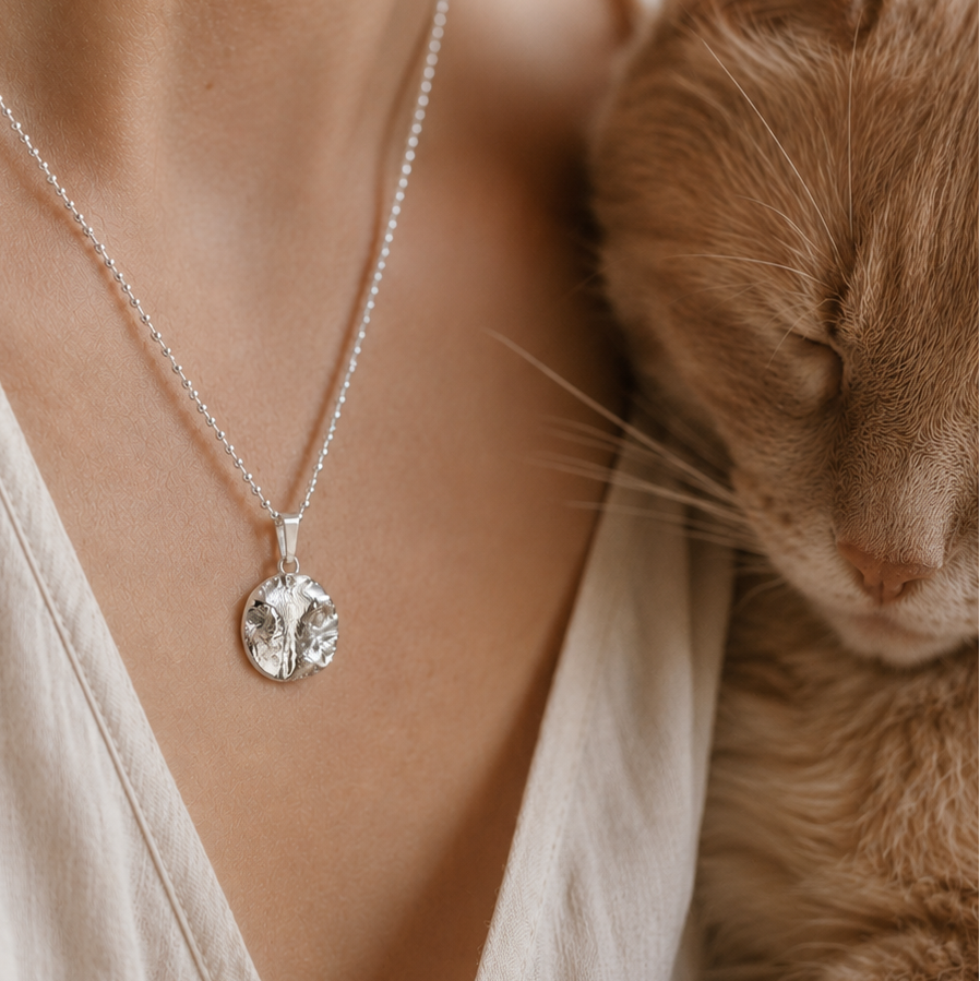 Anhänger mit dem originalen Abdruck einer Katzennase, liegend am hals einer Frau, die mit ihrer Katze kuschelt
